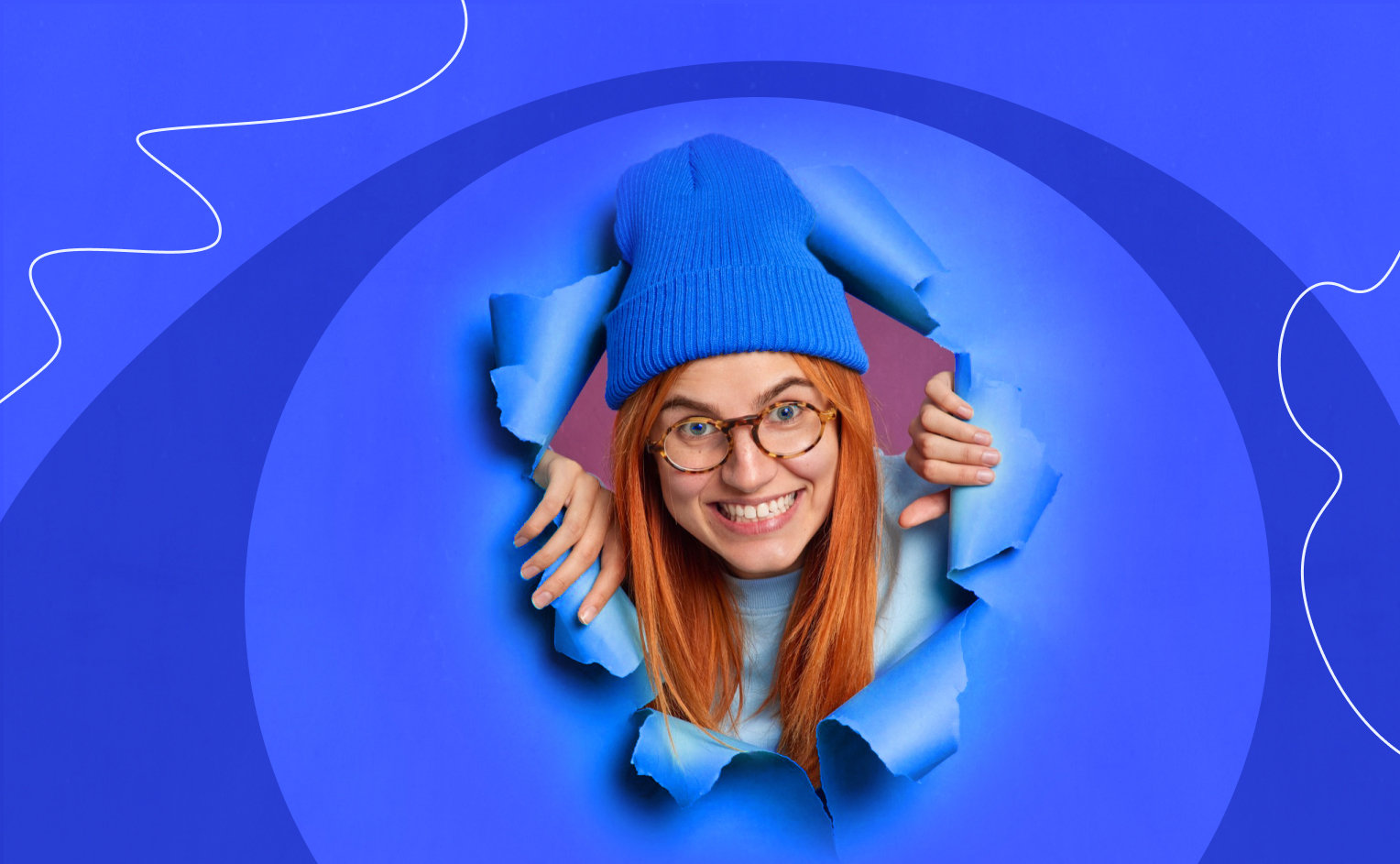 A woman wearing a blue hat emerging through a blue paper wall.